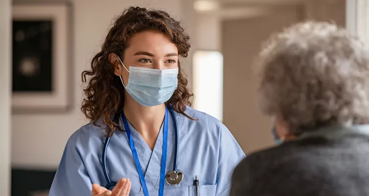 Medical professional in a mask talking to an older person